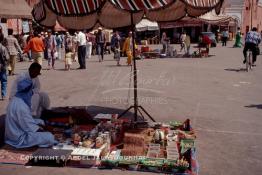 Image du Maroc Professionnelle de  Un homme bleu du désert étale ses produit constitués d'épices, de graines, d'herbes de toutes sorte, de peau de serpent d'oeuf d'autruche à même sur le sol de la fameuse place Jemaa El Fana de Marrakech, la ville touristique du Maroc, Jeudi 19 Mai 1988. (Photo / Abdeljalil Bounhar) 